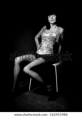 Black and white photo of sexy woman in corset sitting on chair