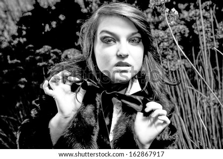 Black and white portrait of elegant woman tying black ribbon bow