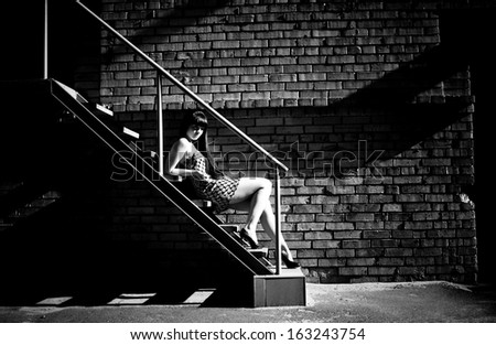 Black and white photo of sexy woman lying on stairs at backyard of building