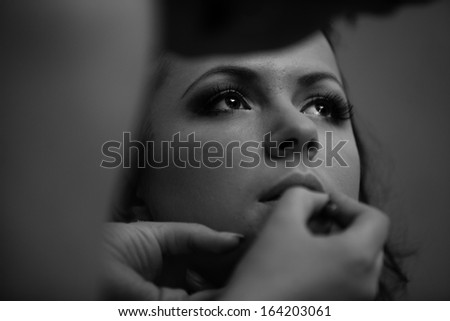 Black and white portrait of makeup artist painting models lips