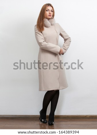 Full length portrait of sexy slim woman wearing long white coat with fur collar