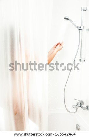 Photo of woman standing in bath behind curtain and having shower