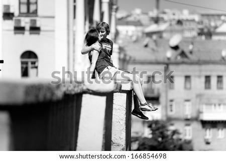Black and white photo of couple in love sitting on rooftop against city view