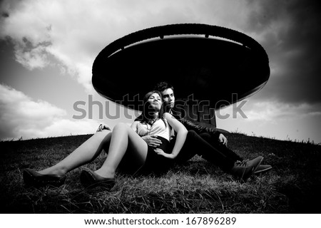 Black and white photo of stylish couple sitting on hill