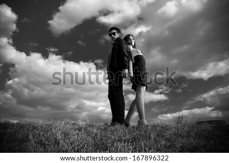 Black and white photo of sexy couple posing on top of hill back to back