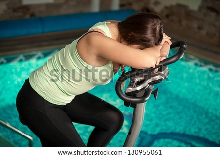 Portrait of exhausted woman spinning pedals on exercise bike