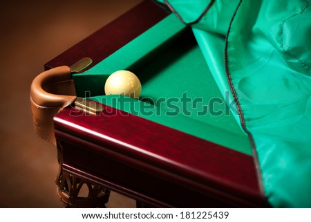 Closeup shot of white ball in billiard pocket on partly covered table with cloth