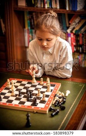 Little girl making move on chess board