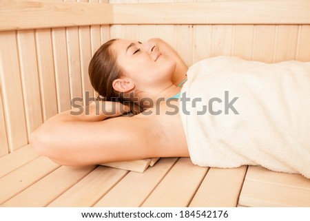 Closeup portrait of brunette woman covered in towel lying at sauna