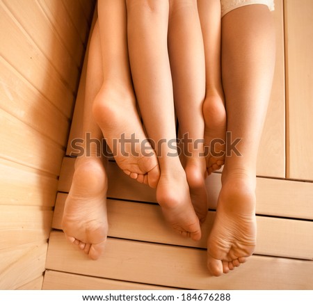 Closeup photo of legs of mother and two girls lying on sauna bench