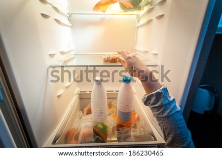 Closeup portrait of female hand taking donut from fridge