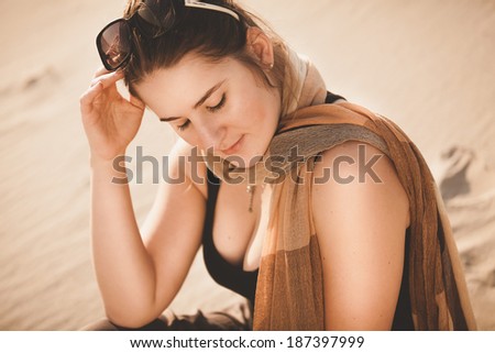 Closeup portrait of woman in sunglasses sitting on sand dune