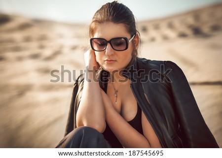 Closeup portrait of sexy woman in sunglasses sitting on sand dune