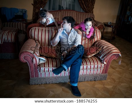 Photo of two daughters disturbing father while watching TV at night