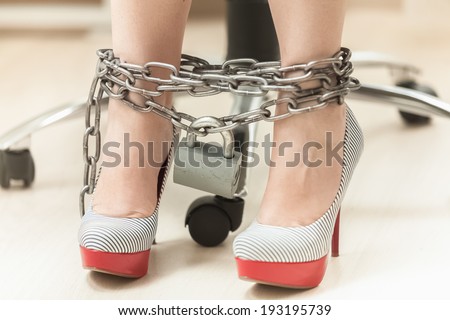 Closeup photo of women legs in high heeled shoes locked by chain