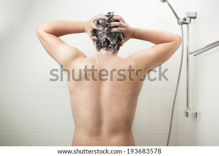 Photo of from back of muscular man washing head at shower