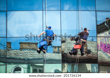 Two men cleaning window facade of skyscraper