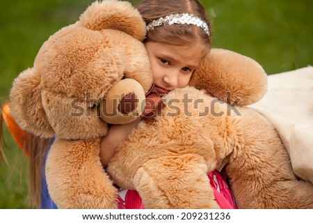 Closeup photo of sad little girl hugging teddy bear