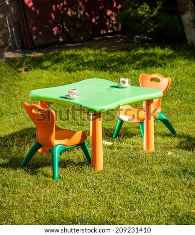 Outdoor shot of children plastic chair and table on grass at yard