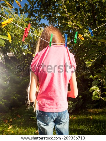 Outdoor shot of little girl hanged by clothespins on rope