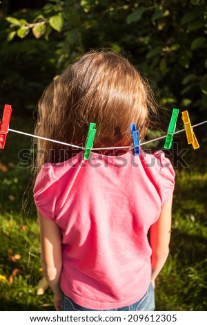 funny shot of girl being hanged by shirt on clothesline