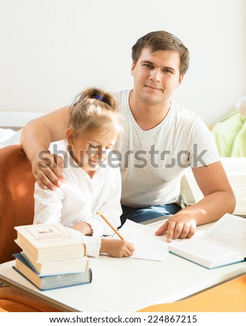 Portrait of handsome man helping daughter with homework