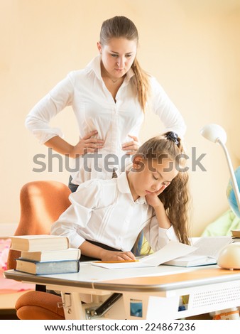 Young mother being angry of daughter sleeping on desk while doing homework