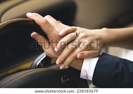 Closeup shot of elegant woman holding hand on men hand while he drives a car