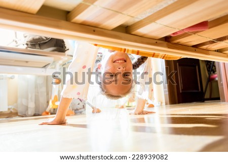 Portrait of little smiling girl looking under bed Portrait of little smiling girl looking under bed