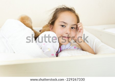 Portrait of little brunette girl woke up at bed at morning