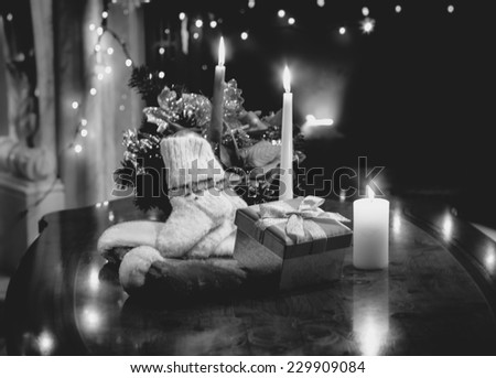 Black and white photo of table decorated with christmas candles, gifts and socks