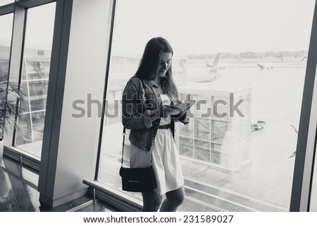 Black and white portrait of young woman using digital tablet at airport