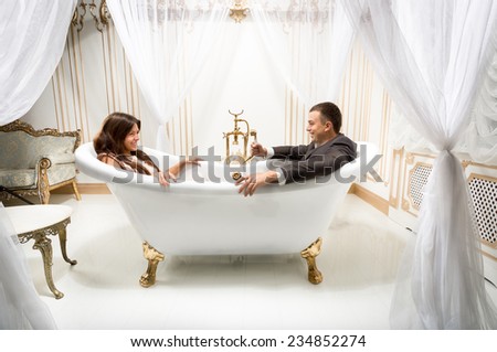 Young clothed man and woman having fun in luxurious bath