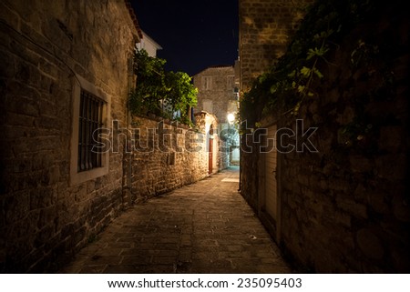 Long old narrow street lit by gas lanterns at night