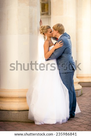 Beautiful newly married couple kissing against old column
