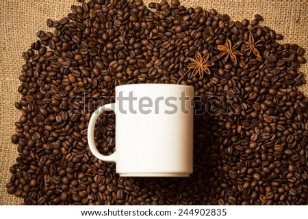 Closeup shot of white mug against of coffee background with star anise