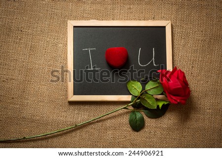 Conceptual photo of declaration of love on blackboard with red rose