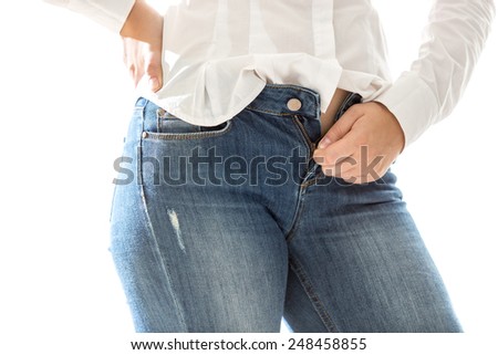 Sexy slim woman in white shirt unbuttoning blue jeans