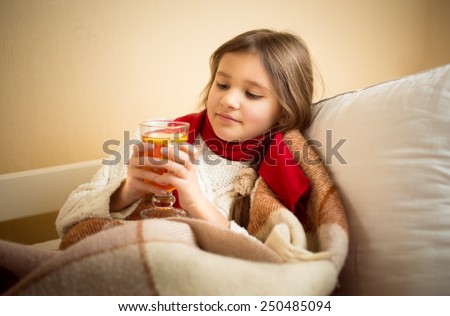 Portrait of cute girl got flu and holding cup of tea at bed