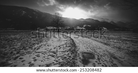 Black and white landscape of snowy road in Alps at sunset
