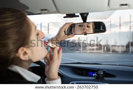 Portrait of beautiful woman applying lipstick in car