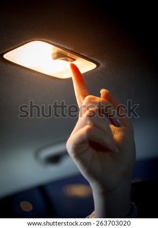 Closeup photo of woman turning light on in car salon