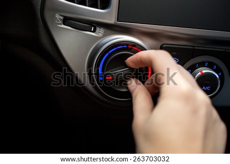 Closeup photo of young woman turning car air conditioner switch