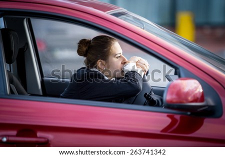 Portrait of tired woman driving car and looking through window