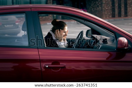 Young businesswoman sitting in car and screaming of fear