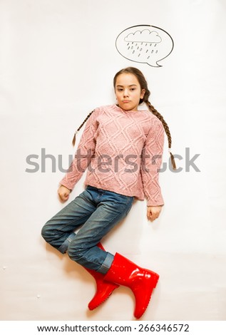 Isolated conceptual shot of sad girl in rubber boots standing under rainy cloud