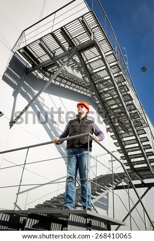 Building control inspector standing on metal staircase and looking at building