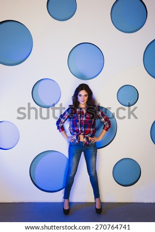 Sexy slim woman in jeans posing against background with blue circles