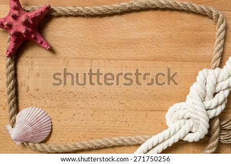 Old wooden boards with rope frame decorated by marine knot and seashells