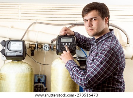 Portrait of young engineer pressing button on control panel with monochrome screen